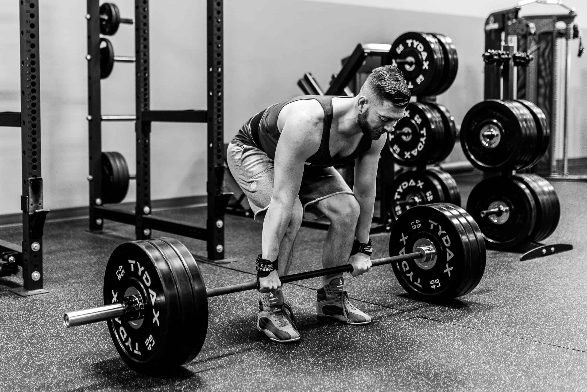The owner Shaun stretching down to grab a barbell for a deadlift excercise